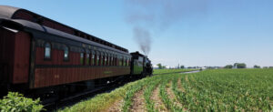 A large, long train traveling on a track with smoke coming out of the front.