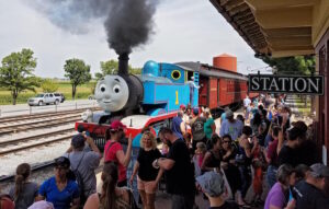 A group of people at East Strasburg Station standing next to the train waiting for the Day Out With Thomas event.