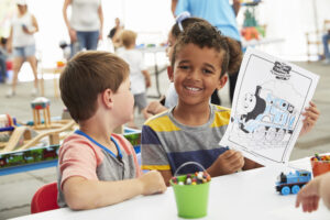 Two little kids coloring a picture of Thomas the Tank Engine.