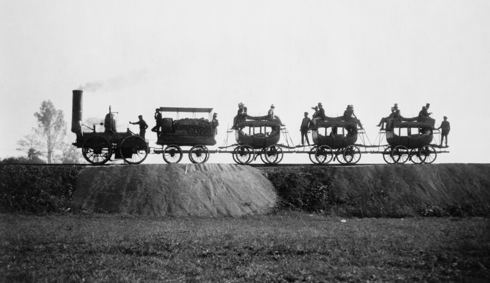 A group of people riding on the back of a 4-part carriage.