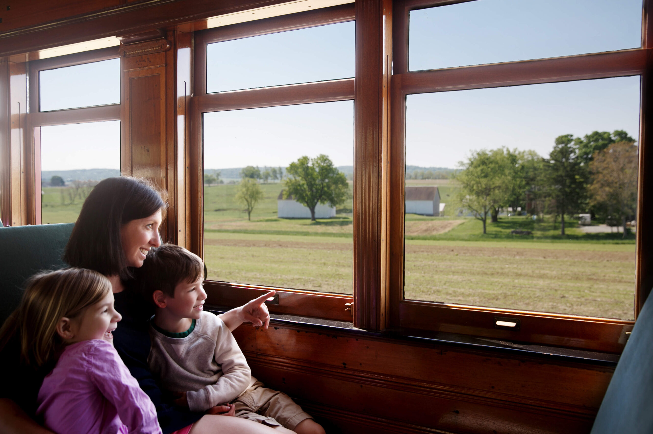 Mother with 2 kids looking out the window of a train.