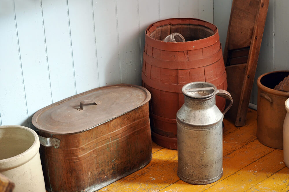 Old mennonite pots and furniture in the corner on a hardwood floor.