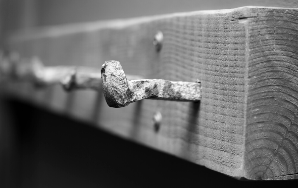 Old railroad spikes attached to a wooden plank to make a DIY coat rack.