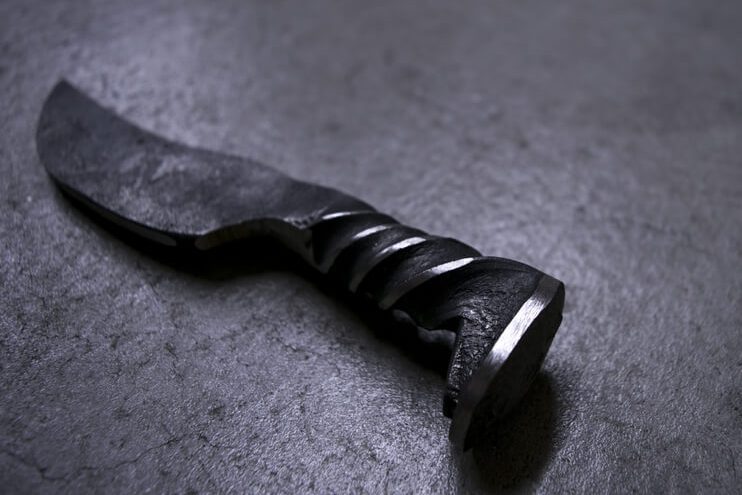 Railroad spike hand forged knife on a table.