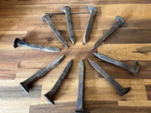 Railroad spikes aligned in a circle on a wood floor.