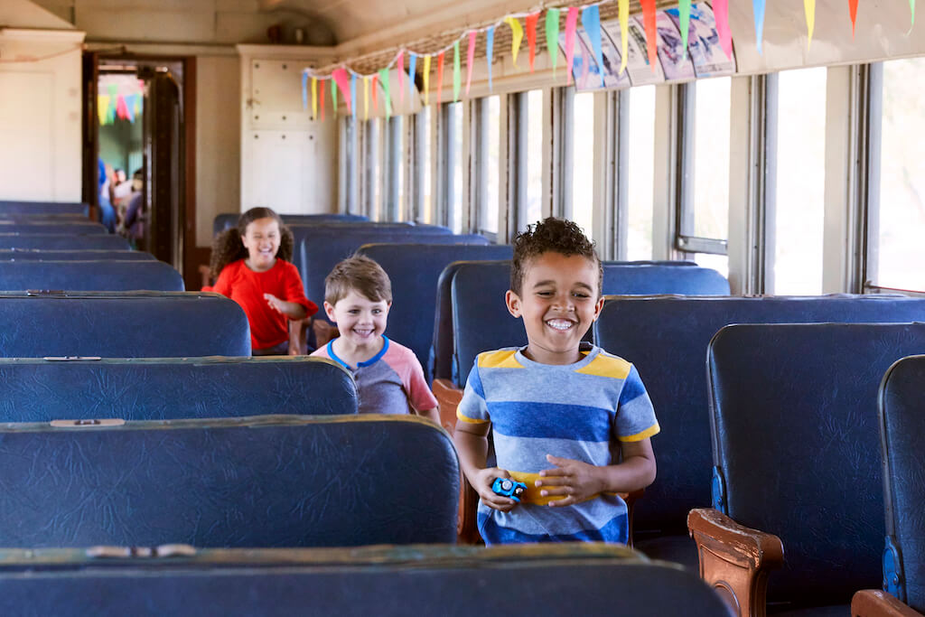 3 kids running down a train aisle