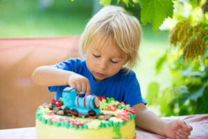 A little boy sitting at a table with a train birthday cake.