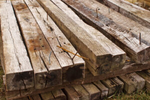 Wooden railroad ties stacked in a pile with nails facing up.