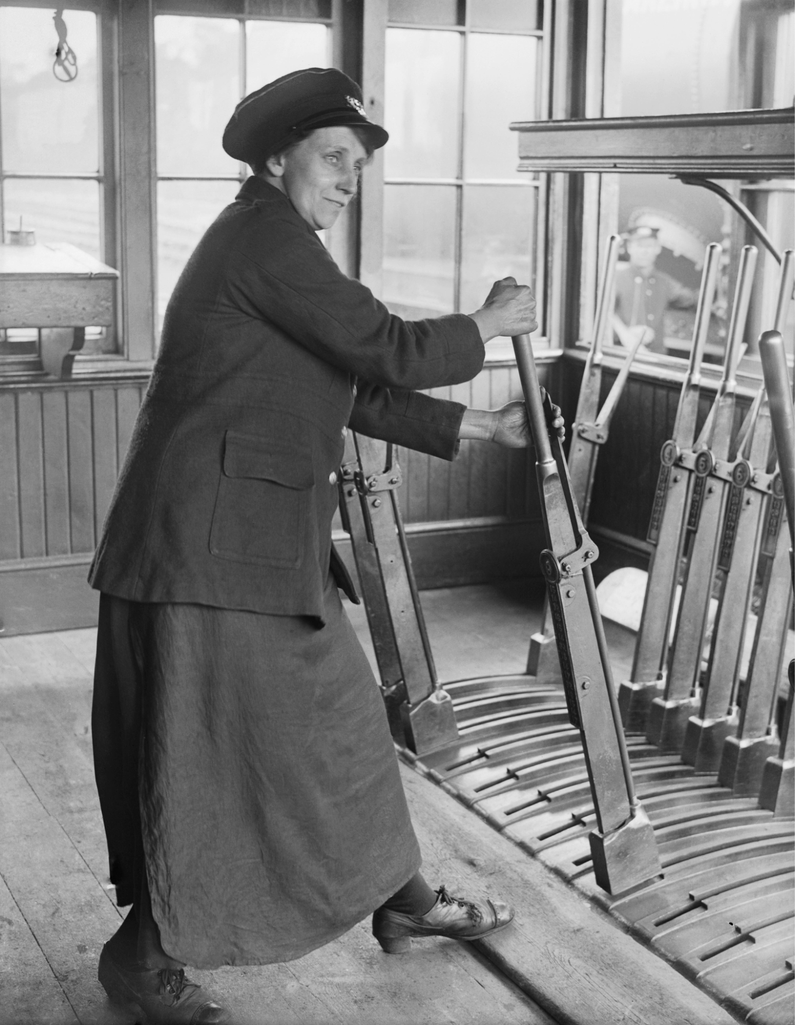 Railroad woman in uniform operating railway signal levers inside a control room.