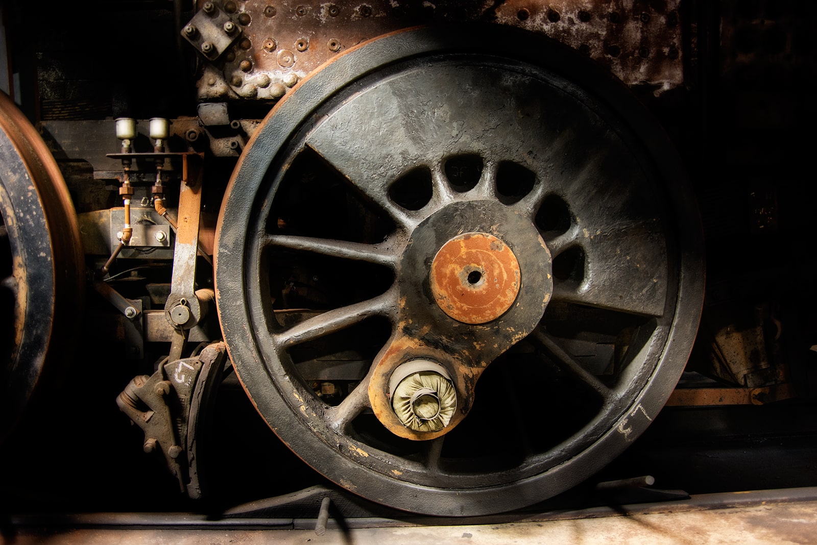 Close-up of a rusty, large train wheel with visible gears and mechanical parts.